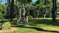 Player winds up for tee shot with teammate watching on