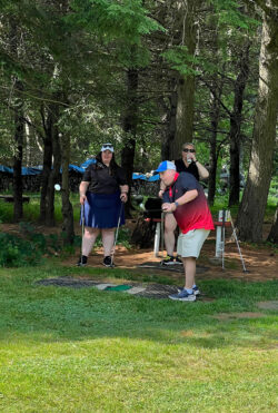 Player tees off towards hole 18 while teammates watch from behind