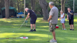 Player putts towards hole while 3 teammates watch