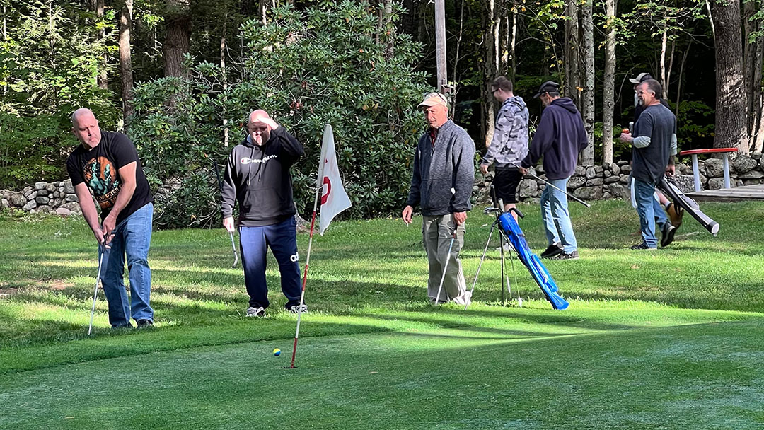 team watches while player chips onto the green