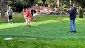 player lines up putt while teammates look on