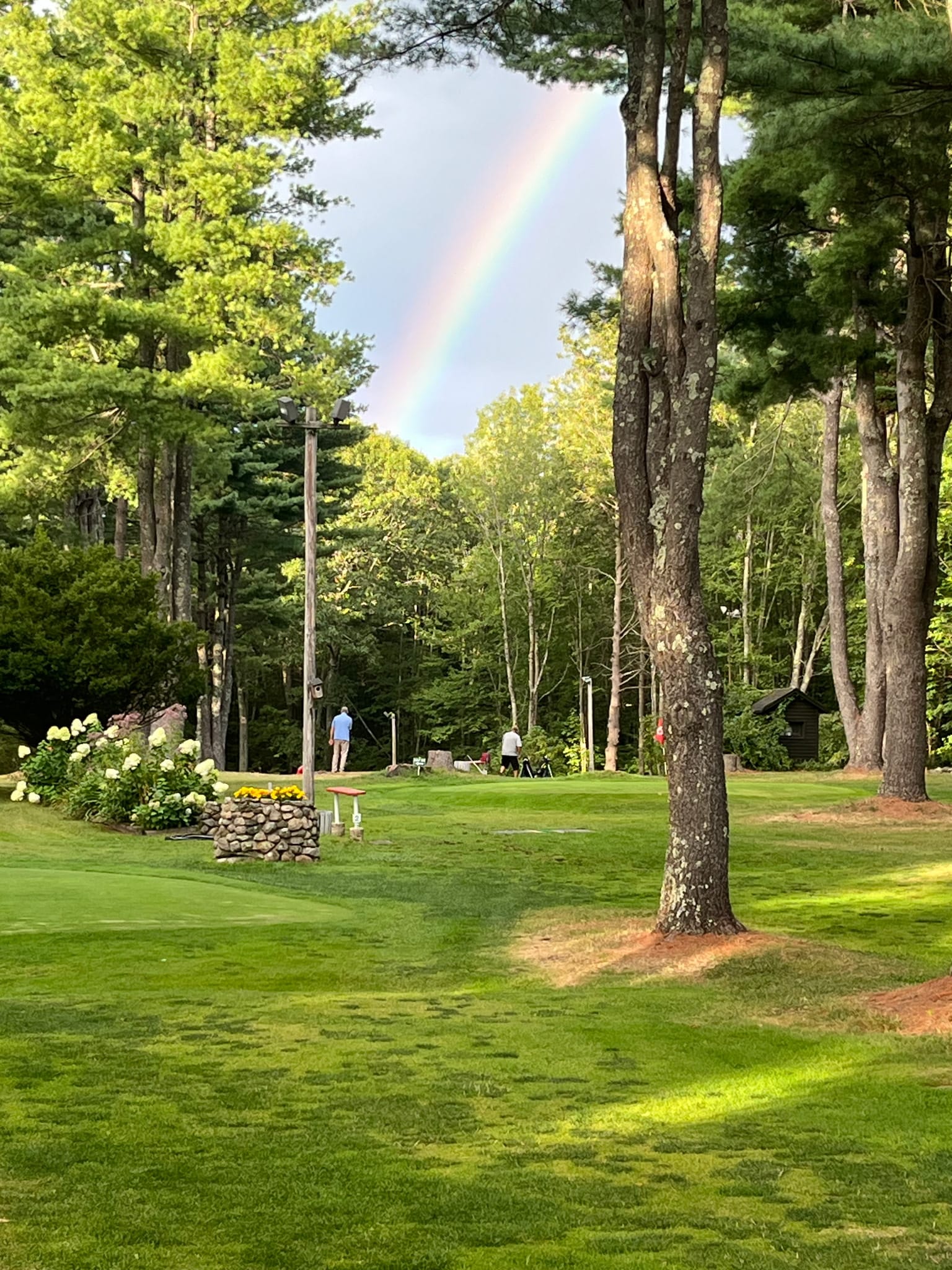 rainbow over the golf course above players in the distance