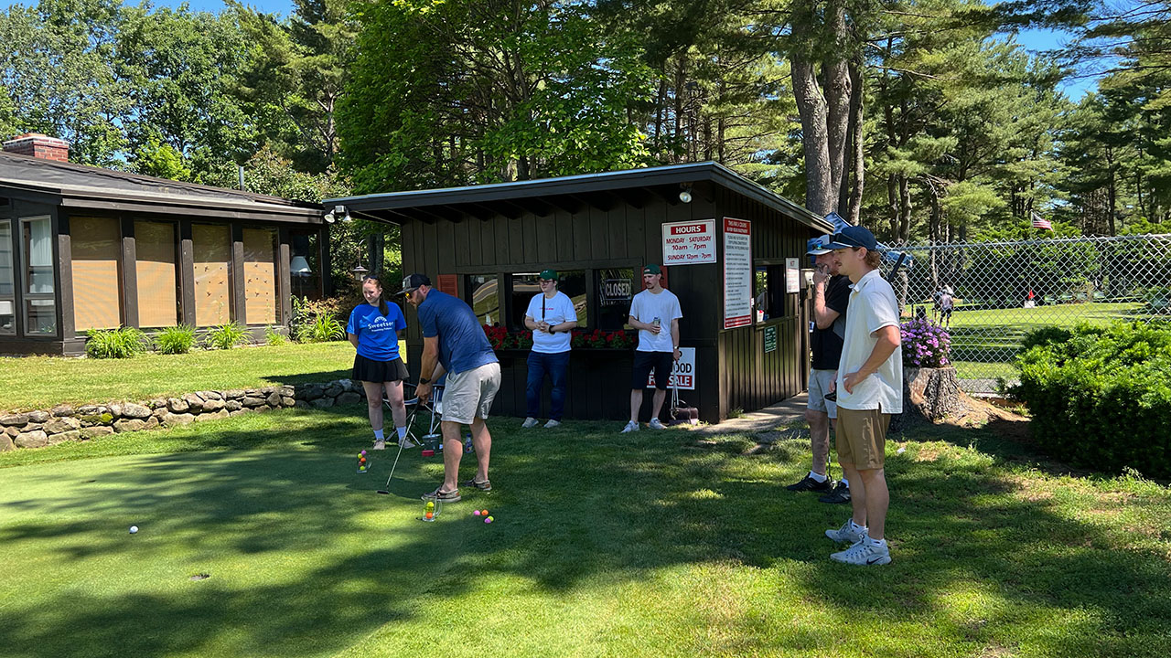 Teammates look on as player tries his luck in the putting contest