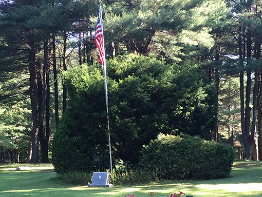 Robert L'Heureux Memorial Stone on golf course in front of flag
